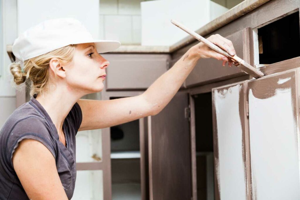 woman doing DIY cabinet painting Paintmaster Services