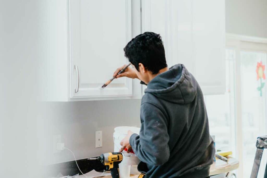 skilled painter from Paintmaster Services painting the kitchen cabinets