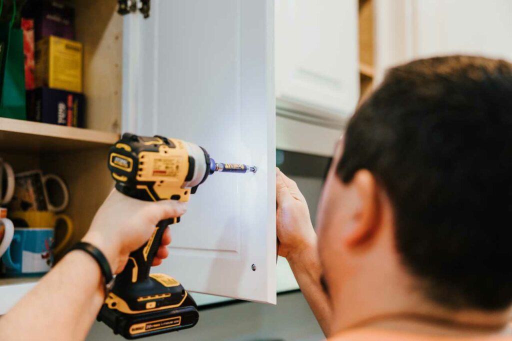 professional kitchen painter drilling the cabinet Paintmaster Services